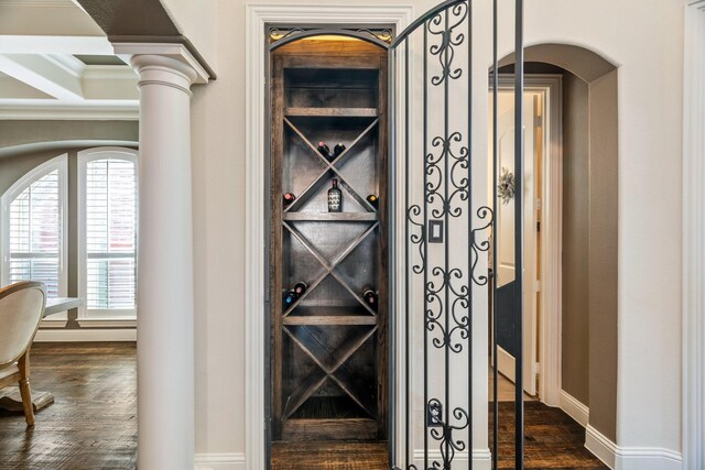 wine room with decorative columns, baseboards, and dark wood-style floors