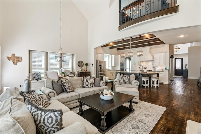 living room featuring a chandelier, dark wood finished floors, a high ceiling, and baseboards