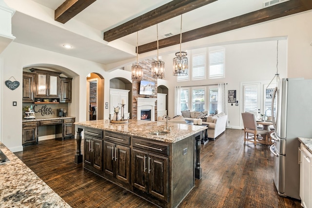 kitchen with visible vents, freestanding refrigerator, a sink, open floor plan, and a large fireplace