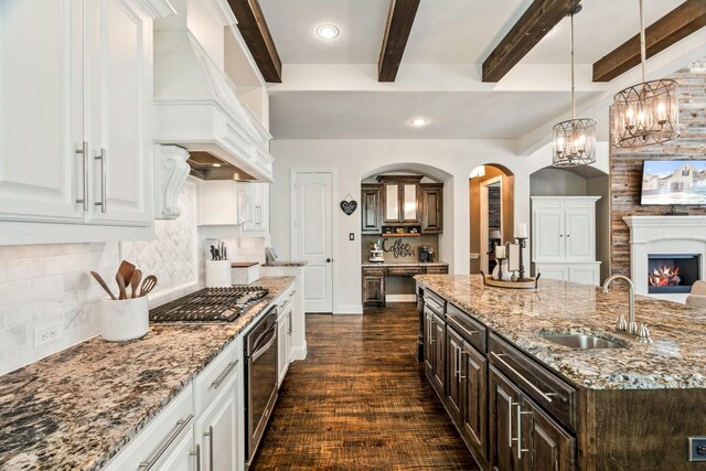 kitchen with premium range hood, white cabinetry, appliances with stainless steel finishes, and a sink