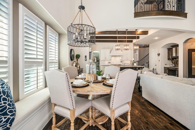 dining space with dark wood finished floors, stairway, a notable chandelier, and arched walkways