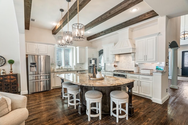 kitchen featuring premium range hood, decorative columns, a sink, appliances with stainless steel finishes, and backsplash