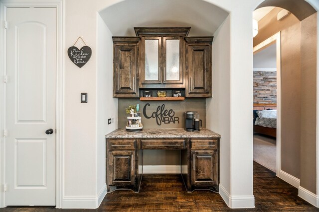 bar featuring arched walkways, dark wood-type flooring, and baseboards