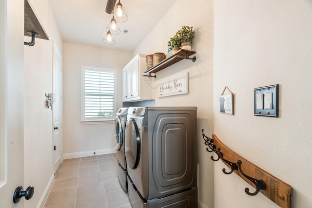 washroom featuring visible vents, cabinet space, light tile patterned floors, baseboards, and washing machine and clothes dryer