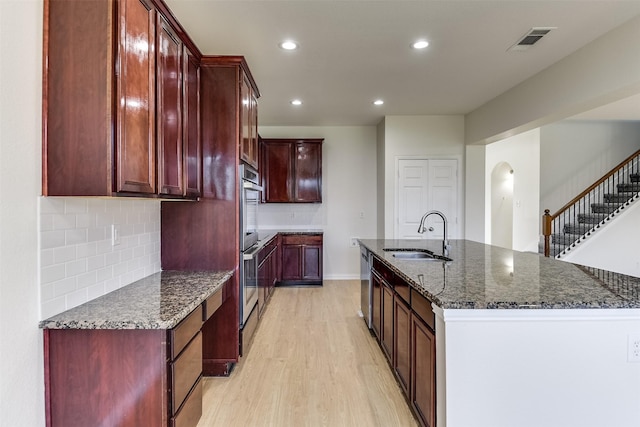 kitchen featuring visible vents, a sink, dark brown cabinets, appliances with stainless steel finishes, and light wood-type flooring