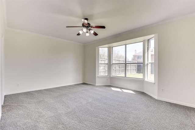 carpeted spare room featuring baseboards, a ceiling fan, and crown molding