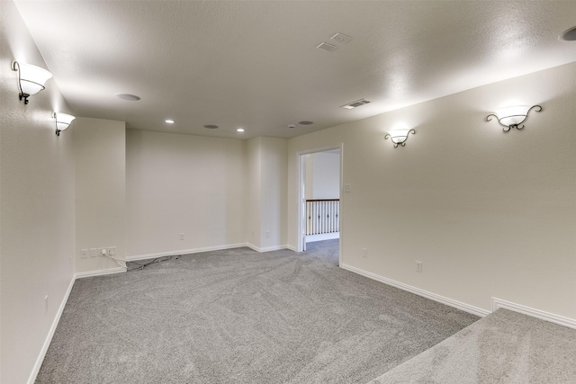 unfurnished room with visible vents, carpet flooring, a textured ceiling, and baseboards