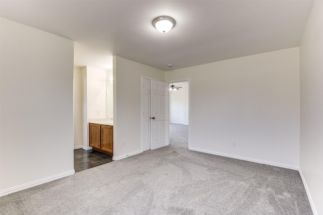 spare room with baseboards and dark colored carpet