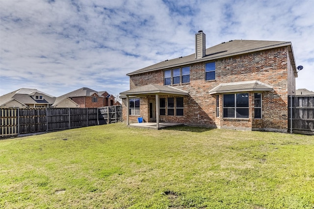 rear view of house featuring a yard, a fenced backyard, and brick siding