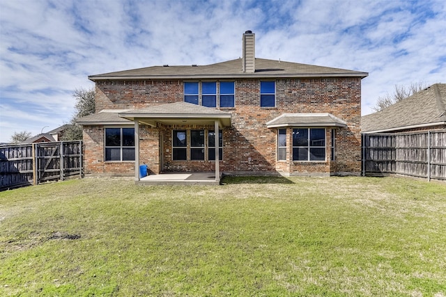 back of property featuring a yard, brick siding, and a fenced backyard