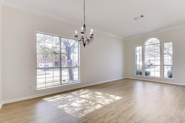 empty room with wood finished floors, a notable chandelier, a healthy amount of sunlight, and visible vents