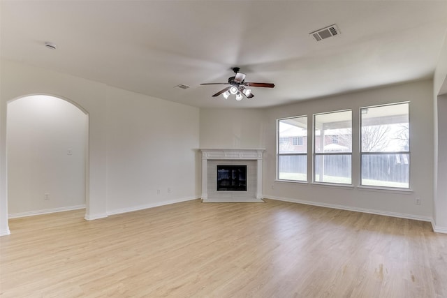 unfurnished living room with visible vents, arched walkways, light wood-style floors, and ceiling fan