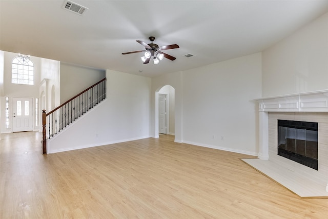 unfurnished living room with baseboards, visible vents, arched walkways, stairs, and light wood-type flooring