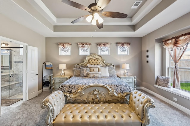 bedroom with a tray ceiling, carpet flooring, baseboards, and visible vents