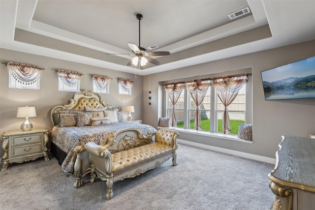 bedroom featuring a tray ceiling, baseboards, visible vents, and carpet floors