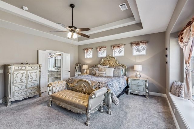 carpeted bedroom with visible vents, a raised ceiling, baseboards, and ceiling fan