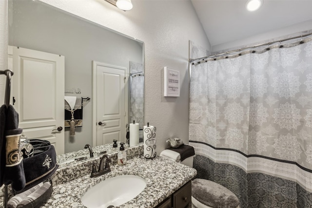 bathroom with a shower with curtain, lofted ceiling, toilet, and vanity