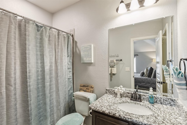 ensuite bathroom featuring a textured wall, vanity, ensuite bathroom, and toilet