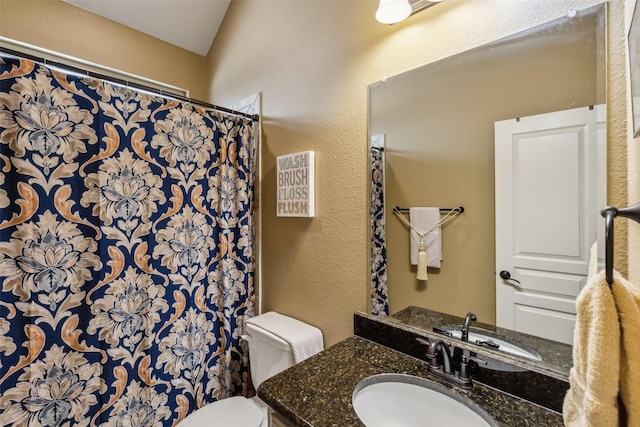 full bathroom with curtained shower, toilet, vanity, and a textured wall