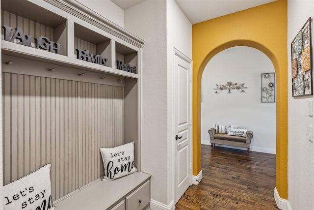 mudroom with dark wood finished floors, baseboards, and arched walkways