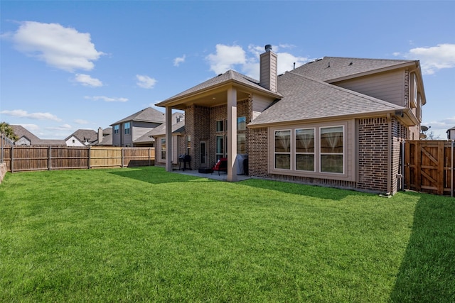 back of property with brick siding, a chimney, a lawn, and a patio area