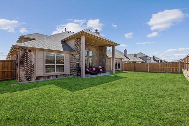 rear view of property with a patio, brick siding, a fenced backyard, and a lawn