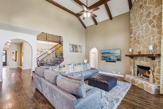 living room featuring wood finished floors, baseboards, high vaulted ceiling, a fireplace, and stairs