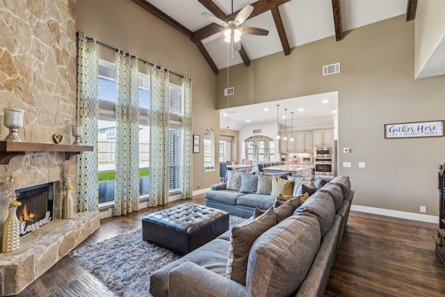 living area with dark wood-type flooring, beamed ceiling, a fireplace, and visible vents