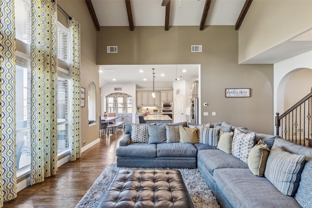 living area featuring dark wood-type flooring, a high ceiling, stairway, and arched walkways