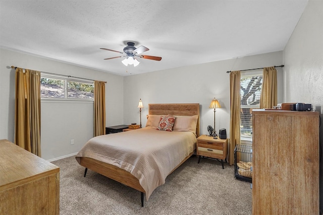 bedroom with multiple windows, light colored carpet, ceiling fan, and a textured ceiling