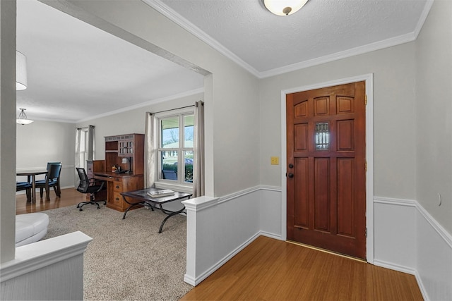 foyer entrance with a textured ceiling, wood finished floors, baseboards, and ornamental molding