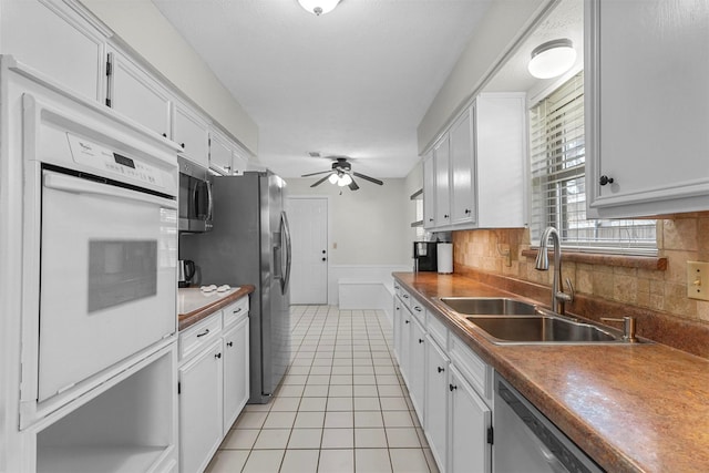 kitchen featuring ceiling fan, light tile patterned floors, appliances with stainless steel finishes, white cabinets, and a sink