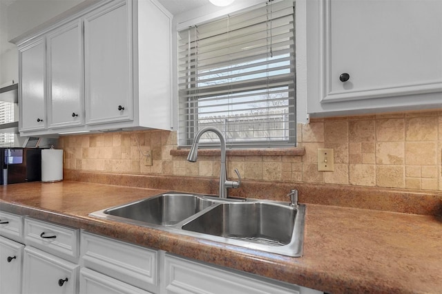 kitchen featuring a sink, decorative backsplash, dark countertops, and white cabinetry