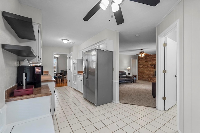 kitchen featuring light tile patterned flooring, white cabinets, stainless steel refrigerator with ice dispenser, light colored carpet, and open floor plan