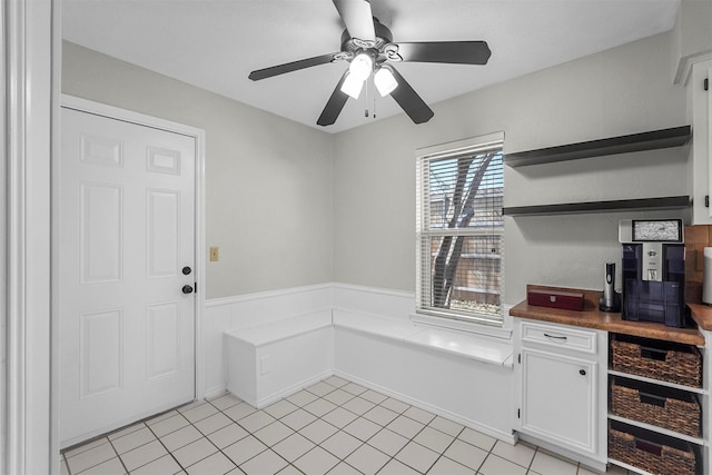 interior space featuring light tile patterned floors, wainscoting, and ceiling fan