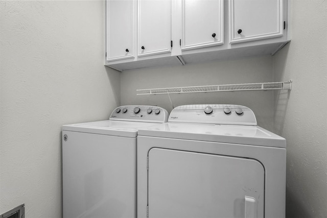 laundry room with cabinet space, independent washer and dryer, and a textured wall