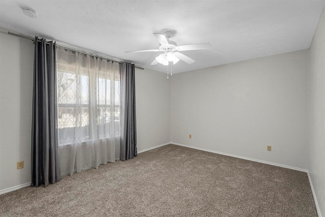 carpeted spare room featuring baseboards and a ceiling fan