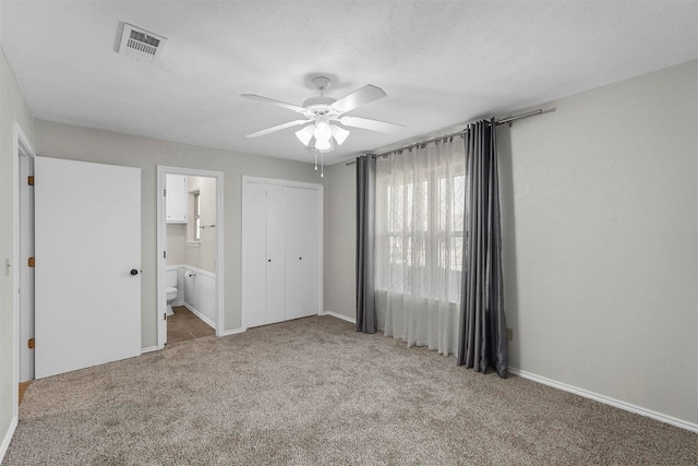 unfurnished bedroom with visible vents, ensuite bath, a closet, carpet, and baseboards