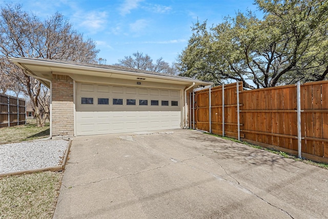 garage featuring concrete driveway and fence