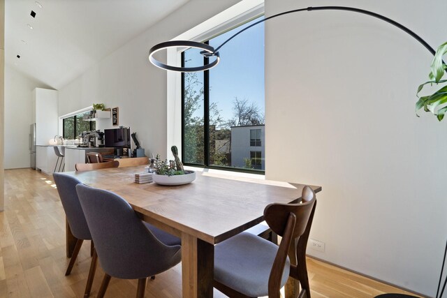 dining space with light wood finished floors and lofted ceiling