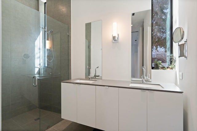 bathroom with a sink, a stall shower, and double vanity