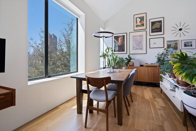 dining space with light wood-style flooring and vaulted ceiling