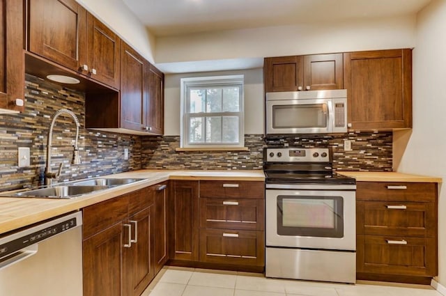 kitchen with light tile patterned floors, a sink, light countertops, appliances with stainless steel finishes, and backsplash