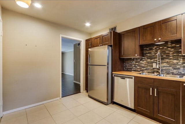 kitchen featuring tasteful backsplash, appliances with stainless steel finishes, light tile patterned flooring, and a sink