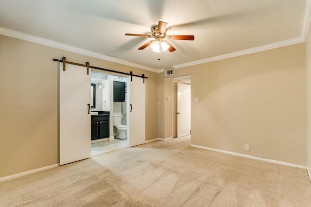 empty room with light carpet, visible vents, a barn door, and ornamental molding