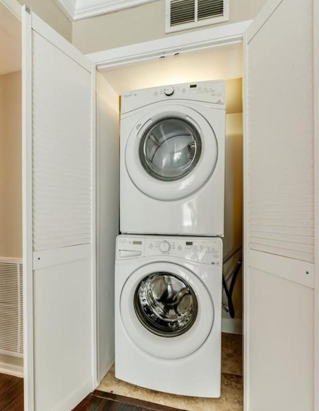 laundry room featuring visible vents, dark wood-style floors, laundry area, and stacked washer / dryer