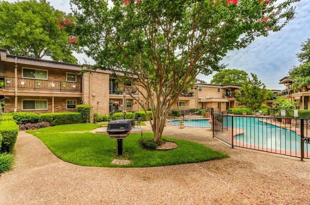 view of community with a swimming pool, a patio, a yard, and fence