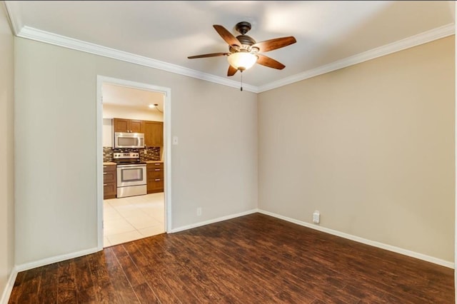 spare room with dark wood finished floors, a ceiling fan, crown molding, and baseboards