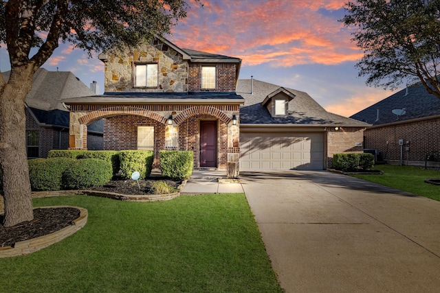 view of front facade with a front yard, concrete driveway, a garage, stone siding, and brick siding