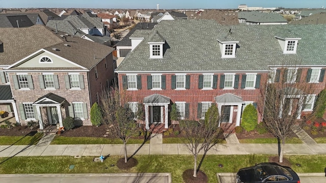 view of front of house featuring brick siding, a residential view, and roof with shingles